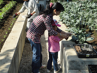 お母さんに教わりながら木酢液の散布（平成22年10月撮影）