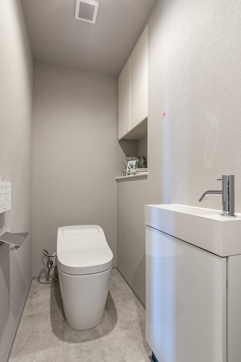 温水洗浄便座付トイレ。上部には収納スペースを設置しており、トイレットペーパーや掃除用品を収納可能。(2022年5月)